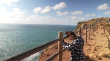 Bir insan telefon kamerasıyla güzelliğini yakalarken nefes kesici sahil şeridinde eğlenir.