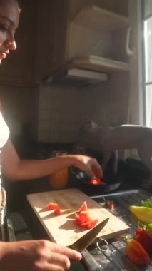 Canlı ve canlı bir mutfak sahnesi. Taze malzemeler, çeşitli yemek pişirme faaliyetleri ve neşe dolu.