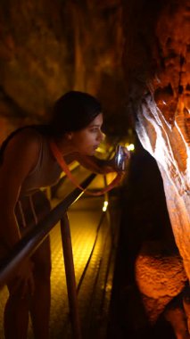 Bir kişi, çarpıcı jeolojik özelliklerle çevrili eşsiz mağara oluşumlarını el feneriyle gözlemliyor.