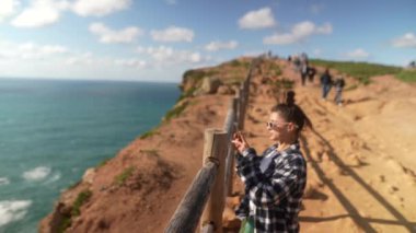 Genç bir kadın aşağıdaki uçsuz bucaksız okyanusu gören bir uçurumdan nefes kesici ve çarpıcı manzaralar yakalıyor.