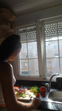 Rengarenk sebzelerle dolu parlak bir mutfak. Pencereden içeri süzülen sıcak güneş ışığıyla aydınlatılıyor.