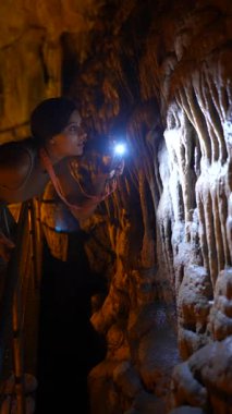 Bir insan loş bir mağaradaki karmaşık mağara yapılarını araştırır, güzelliği ön plana çıkarır..