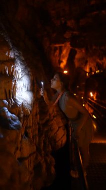 Tek başına ışık saçan biri mağara duvarını aydınlatıyor çarpıcı ve karmaşık sarkıt oluşumlar sergiliyor.