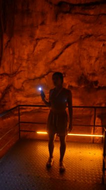 Maceracı bir insan, engebeli arazide parlak bir el feneri tutarak mağaraların gizli derinliklerini cesurca keşfeder.