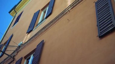 Açık mavi gökyüzüne karşı geleneksel panjurları gösteren canlı ve renkli şehir cephesini keşfedin.