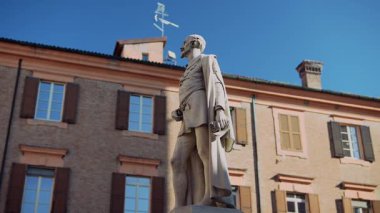 Çarpıcı bir manzara, parlak güneş ışığında tarihi bir arkaplan karşısında güzel bir heykel sergiliyor.