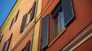 Mavi panjurlarla süslenmiş canlı turuncu bir duvar klasik mimarinin cazibesinin mükemmel bir örneği.