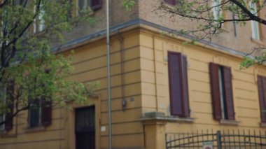 Büyüleyici, resim gibi sarı bir ev canlı yeşil ağaçlarla harmanlanmış sakin bir şehir cazibesini yakalıyor.