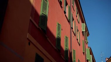 Şaşırtıcı derecede güzel kırmızı binalar büyüleyici yeşil panjurlarla süslenmiş açık mavi gökyüzüne karşı kurulmuş.