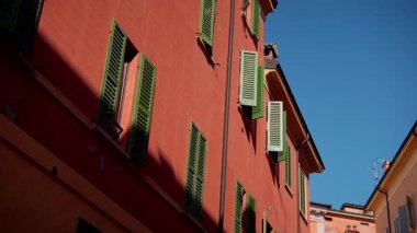Güneşli mavi gökyüzünün altında büyüleyici yeşil panjurlarla süslenmiş renkli bir binanın nefes kesici ve büyüleyici manzarası.