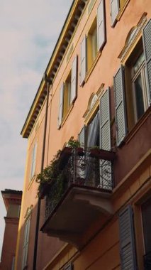 Canlı bitkilerle bezenmiş büyüleyici bir balkon, canlı bir İtalyan binasının ön cephesinde güzel bir yere yerleştirilmiştir.