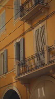 Canlı ve göz alıcı sarı bir bina zarif balkonlarını sergiliyor, şık panjurlarla süslenmiş.