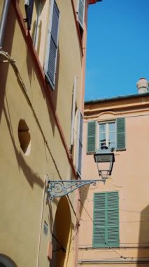 Tuhaf ve büyüleyici küçük bir ara sokakta açık mavi gökyüzünün altında antika bir sokak feneri olan renkli binalar var.