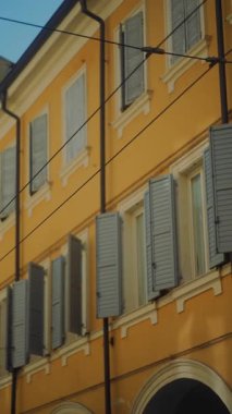 Canlı sarı duvarları ve şık panjurları olan pitoresk bir bina davetkar bir atmosfer yaratıyor.