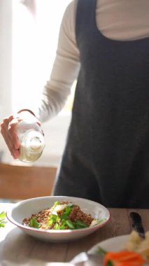 Güzel, güneşli bir mutfakta, kendini adamış bir şef, yeni hazırlanmış bir yemeğin üzerine aromalı tatlar serpiştirir.