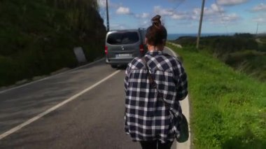 Çevresi yeşillik ve güzel bir okyanus manzarasıyla çevrili dolambaçlı bir yolda güzel bir yürüyüşün tadını çıkaran bir insan..