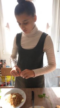 Genç bir insan ustalıkla taze malzemeler hazırlar. Parlak bir mutfakta mutfak sanatını sergiler..