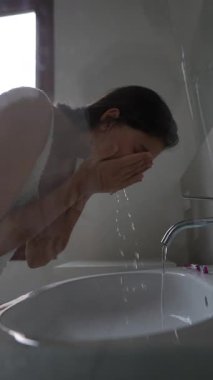 Huzurlu bir anda, bir kadın nazikçe yüzünü güzel, parlak ve davetkar bir banyo alanında temizler.