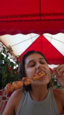 Heyecanla dolu canlı bir açık hava yemek atmosferinde şişin tadını çıkaran bir kadın.