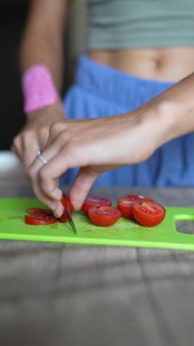 Bir insan taze domatesleri canlı ve renkli bir kesim tahtasıyla ustalıkla dilimleyip sağlıklı yemek hazırlıyor.
