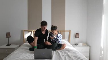 Bir çocukla bir yetişkinin laptoplarını yatakta paylaşırken, birlikte geçirdikleri zamanın keyfini çıkardıkları yürek ısıtan bir sahne..