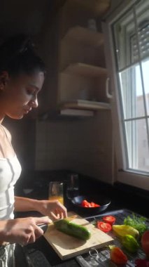 Odaklanmış bir birey, sağlıklı bir yaşam tarzını kucaklamak için parlak bir mutfakta renkli sebzeleri ustaca hazırlıyor.