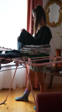 Rahat bir ortamda, genç bir kadın yeni yıkanmış giysileri katlıyor, günlük hayatın keyfine varıyor.