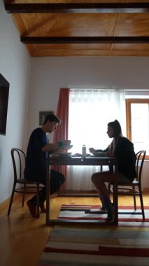 İki insanın, yumuşak, doğal bir ışıkla güzel bir sofrada birlikte yemek yediği samimi bir sahne.