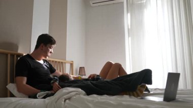 Rahat bir çift, sıcak doğal ışıkla dolu parlak ve rahat bir yatak odasında birlikte vakit geçirmekten zevk alır.