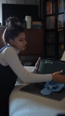 Çalışkan ve odaklanmış bir birey, mikrofiber bez kullanarak özenle dizüstü bilgisayarını temizler.