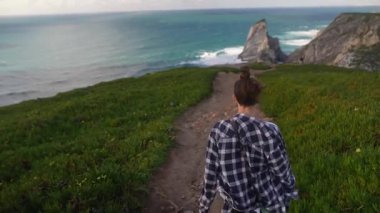 Bir insan yemyeşil ve çarpıcı okyanus manzaralı manzaralı manzaralı manzaralı manzaralı manzaralı manzaralı bir sahil yolunda gezinir.