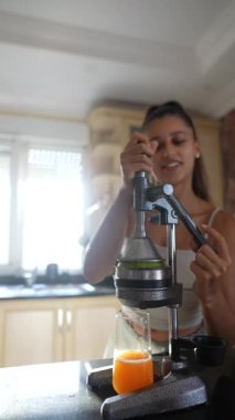 Parlak bir mutfakta meyve sıkma sanatını sergileyen bir kadın taze malzemeler ve canlı meyve suyu sergiliyor..