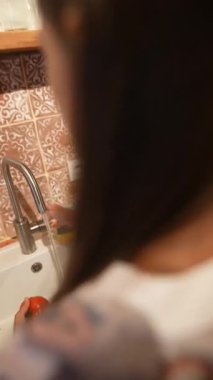 Sıcak bir mutfakta, bir kadın taze ürünleri dikkatlice yıkar, sağlıklı yemek pişirmenin ve beslenmenin değerini vurgular.