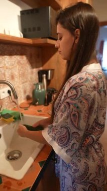 Sıcak bir mutfak ortamında, bir kadın özenle lavaboda taze sebze çeşitleri hazırlıyor.