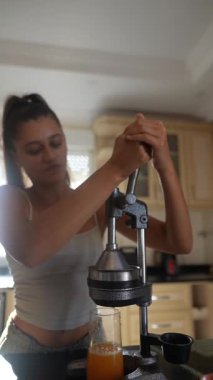 Parlak ve davetkar bir mutfakta, bir insan ferahlatıcı, taze meyve suyu elde etmek için ustaca bir el sıkacağı kullanır.