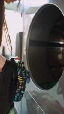 Genç bir birey bir çamaşır makinesine bağlanır, çağdaş çamaşır uygulamalarını eylem halinde gösterir.