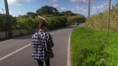 Huzurlu bir şekilde yeşil ve mavi gökyüzüyle çevrili huzurlu bir yolda yürüyen bir insan görüntüsü.