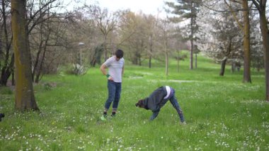 Bereketli yeşil bir parkta, iki genç yetişkin dinamik egzersizler yaparak sağlık ve uygunluklarını arttırıyorlar.