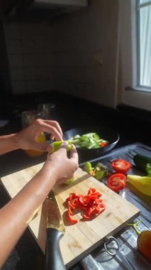 Parlak, neşeli bir mutfakta besleyici bir yemek hazırlamak için çeşitli canlı sebzeleri doğramak.