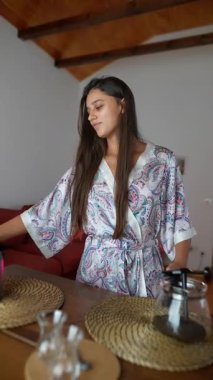 Bir kadın kahvesini dikkatlice ev ortamında hazırlar, sakin bir sabah rutinini mükemmel bir şekilde gözler önüne serer.