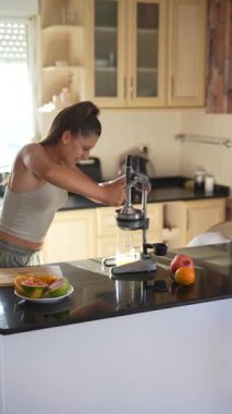 Bir kadın neşeli bir şekilde canlı meyveler ve renkli malzemelerle dolu şık bir mutfakta taze meyve suyu yapıyor.