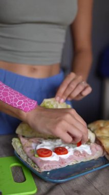 Canlı ve renkli bir sandviç, taze marul, olgun domates ve kremalı malzemelerle ustalıkla hazırlanıyor.