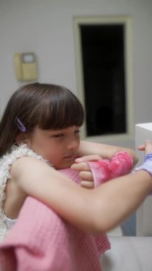 Bir kız kollarını zarif bir şekilde renkli eldivenlerle süslenmiş rahat bir yerde, yumuşak pembe kumaşın üzerinde dinlendiriyor.