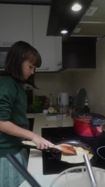 Çağdaş bir mutfakta ustalıkla yemek pişiren genç bir kız aşçılık yeteneği ve yaratıcılık sergiliyor..