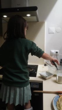 Genç bir aşçı ustaca hazırlar ve lezzetli gözlemeler sunar, rahat bir mutfakta yemek pişirme becerilerini sergiler.