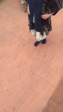 Genç bir insan kendine güvenerek çatıda poz veriyor ve geleneksel elementlerle eşsiz bir kıyafet sergiliyor..