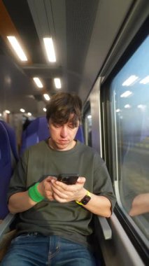 Genç bir adam akıllı telefonunu kullanarak tren yolculuğuna dalmıştı. Manzaralı bir yolculuktu.