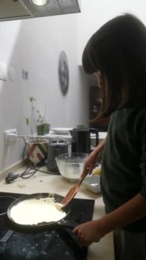 Sıcak ve davetkar bir mutfakta yetenekli genç bir şef lezzetli ve lezzetli krepler hazırlar.