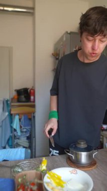 Genç bir insan mutfağında yemek hazırlar, mutfak dinamiklerini gösterir ve ev yemeği hazırlar..