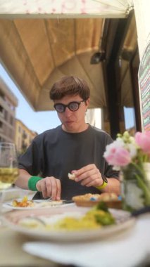 Genç bir adam, lezzetli yemekler ve hoş bir ortam ile çevrili bir kafede yemeğinin tadını çıkarıyor.